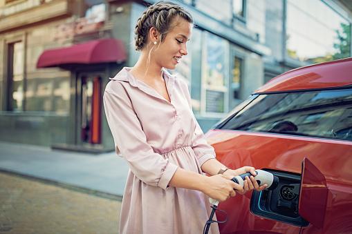 Woman charging her car in the city with on street charging