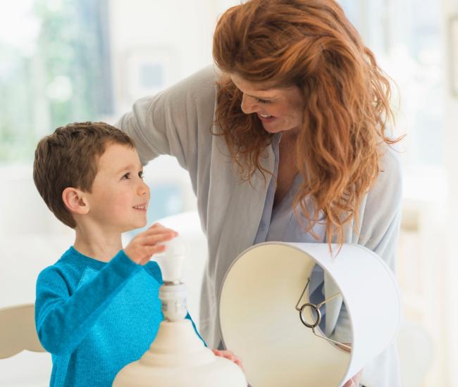 A woman teaching a kid how change the light bulb