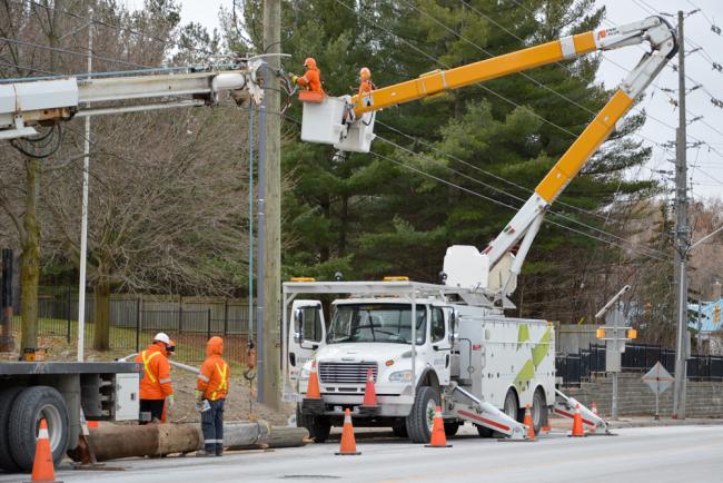 alectra workers in a bucket truck above the street working on power cables