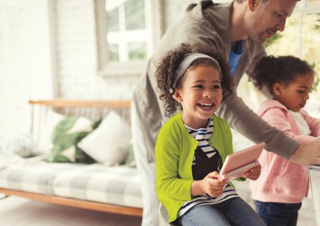 happy young girl smiling as she plays with a hand held video game